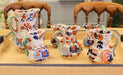 Set of ceramic pitchers with floral patterns on a wooden table.