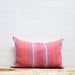 red handwoven textile with blue and white stripes on oblong pillow