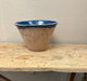 Large ceramic bowl with blue interior on a wooden table against a beige wall.