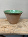 Vintage ceramic planter with green top and brown base on a wooden table.