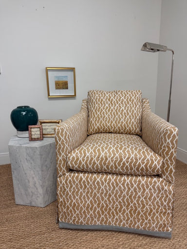 Patterned armchair against a white wall with decorative items.