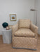 Patterned armchair against a white wall with decorative items.