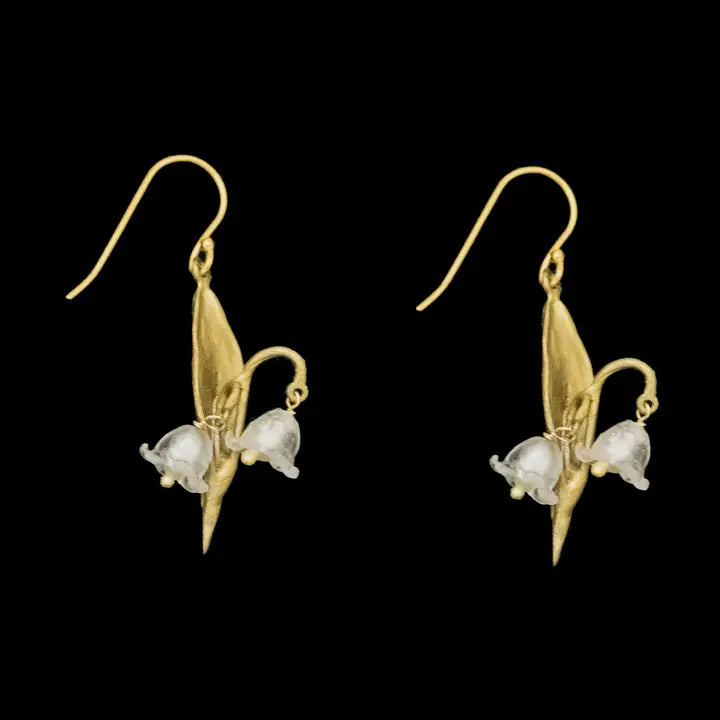 Gold earrings with lily floral design on a black background