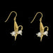 Gold earrings with lily floral design on a black background