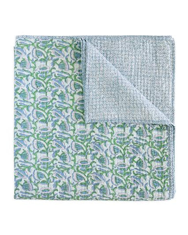 Folded quilt with green and blue pattern on a white background