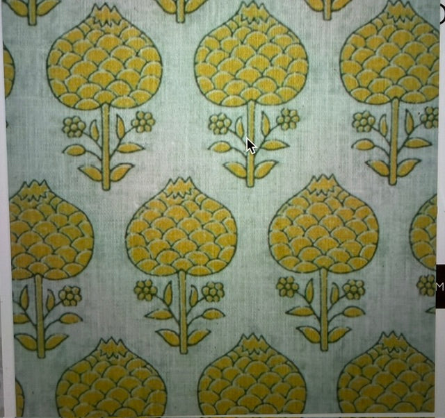 A close-up of a patterned fabric or wallpaper showing a repeating mid-century floral motif in mustard yellow and olive green on a pale sage green background.