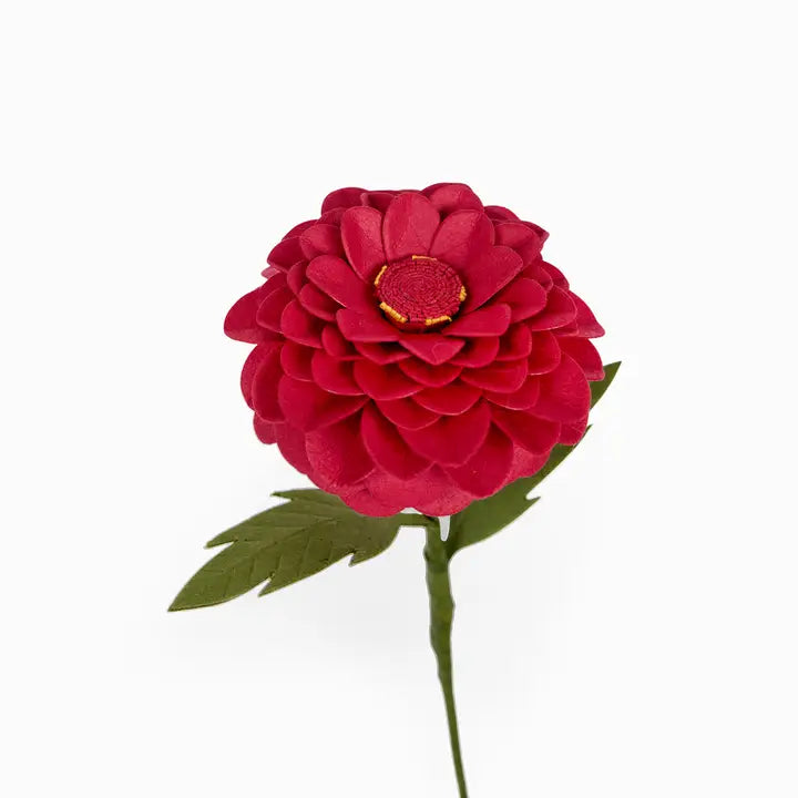A single artificial flower with layered deep red petals, a textured red center with a gold ring, and green leaves on a stem, isolated on a white background.