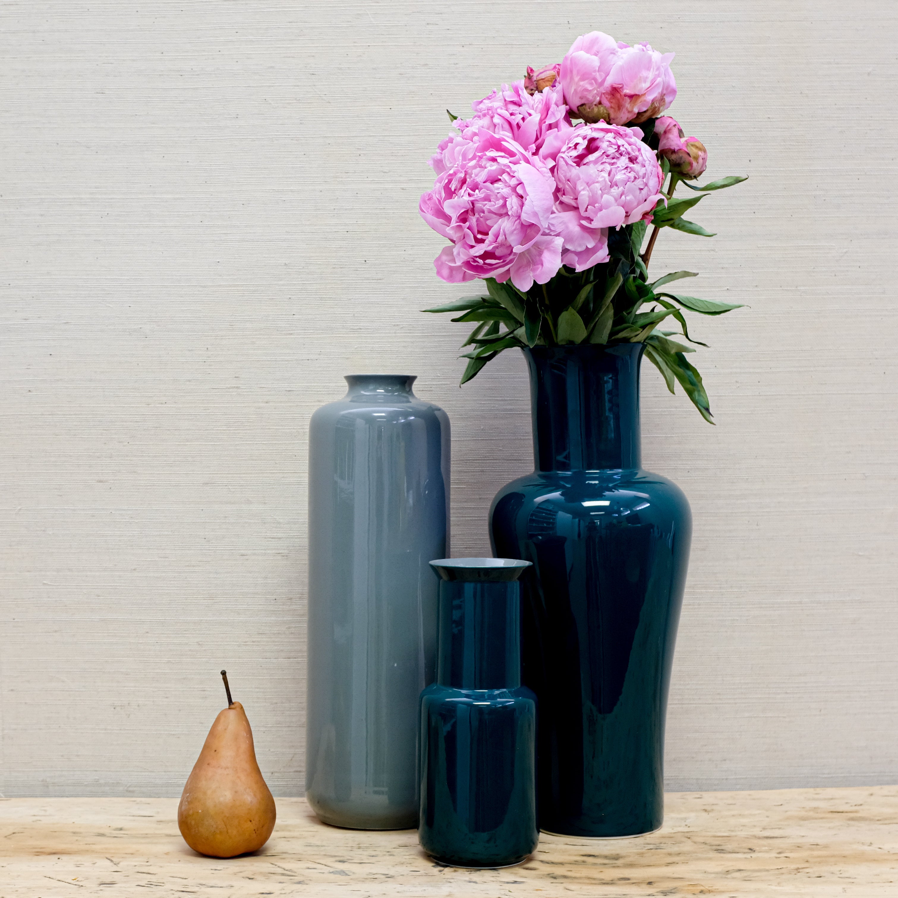 trio of glossy vases with peonies and a pear