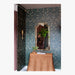 Decorative room with floral wallpaper, a mirror, and a wicker table.