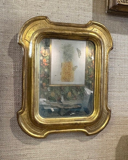 Decorative gold-framed mirror on a textured wall