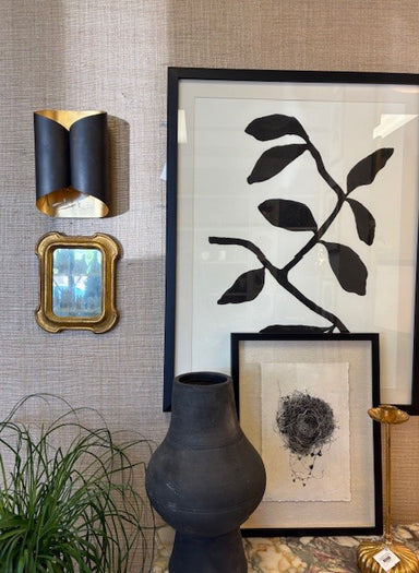 Decorative wall with framed artwork, a vase, and a small mirror.