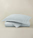 Light blue textured quilt and pillow on a beige background