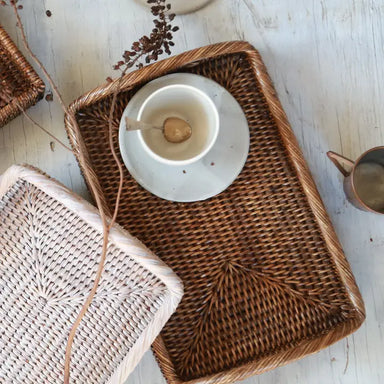 Woven tray with a white dish and spoon on a light wooden surface