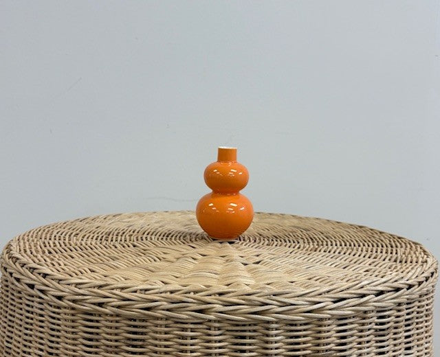 orange double gourd vase on wicker table with white background