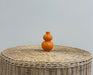 orange double gourd vase on wicker table with white background