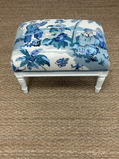 Small ottoman with blue floral pattern on a brown carpet