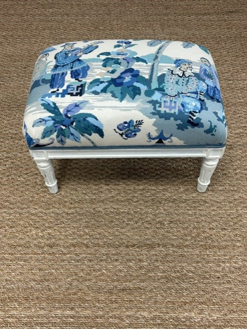Small ottoman with blue floral pattern on a brown carpet