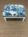 Small ottoman with blue floral pattern on a brown carpet