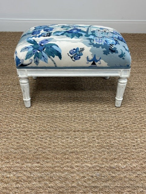  Ottoman with blue floral pattern on a brown carpet