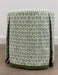 Ottoman with a patterned green and gray cover on a carpeted floor.