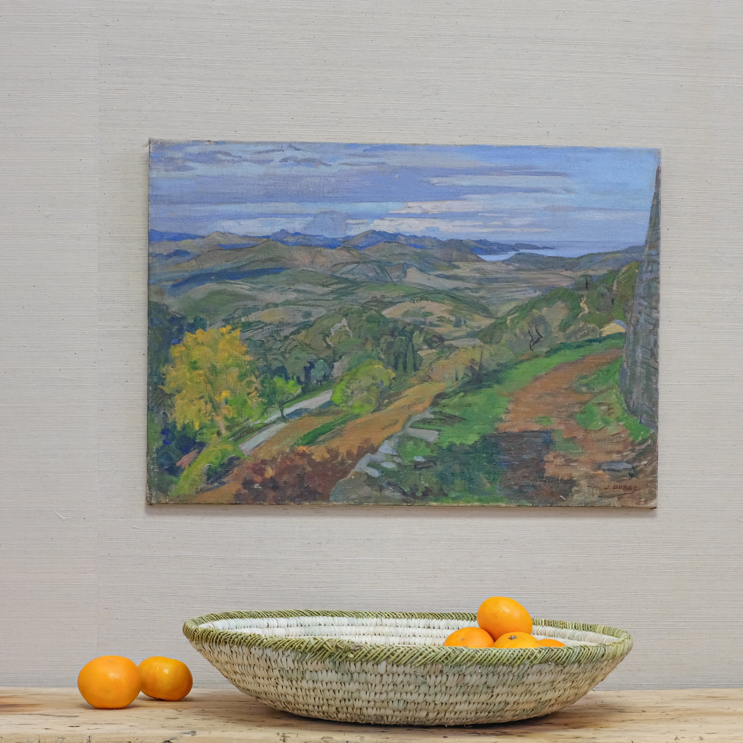 landscape oil painting hanging above low basket of tangerines