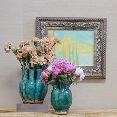 oil painting displayed with two green vases of flowers