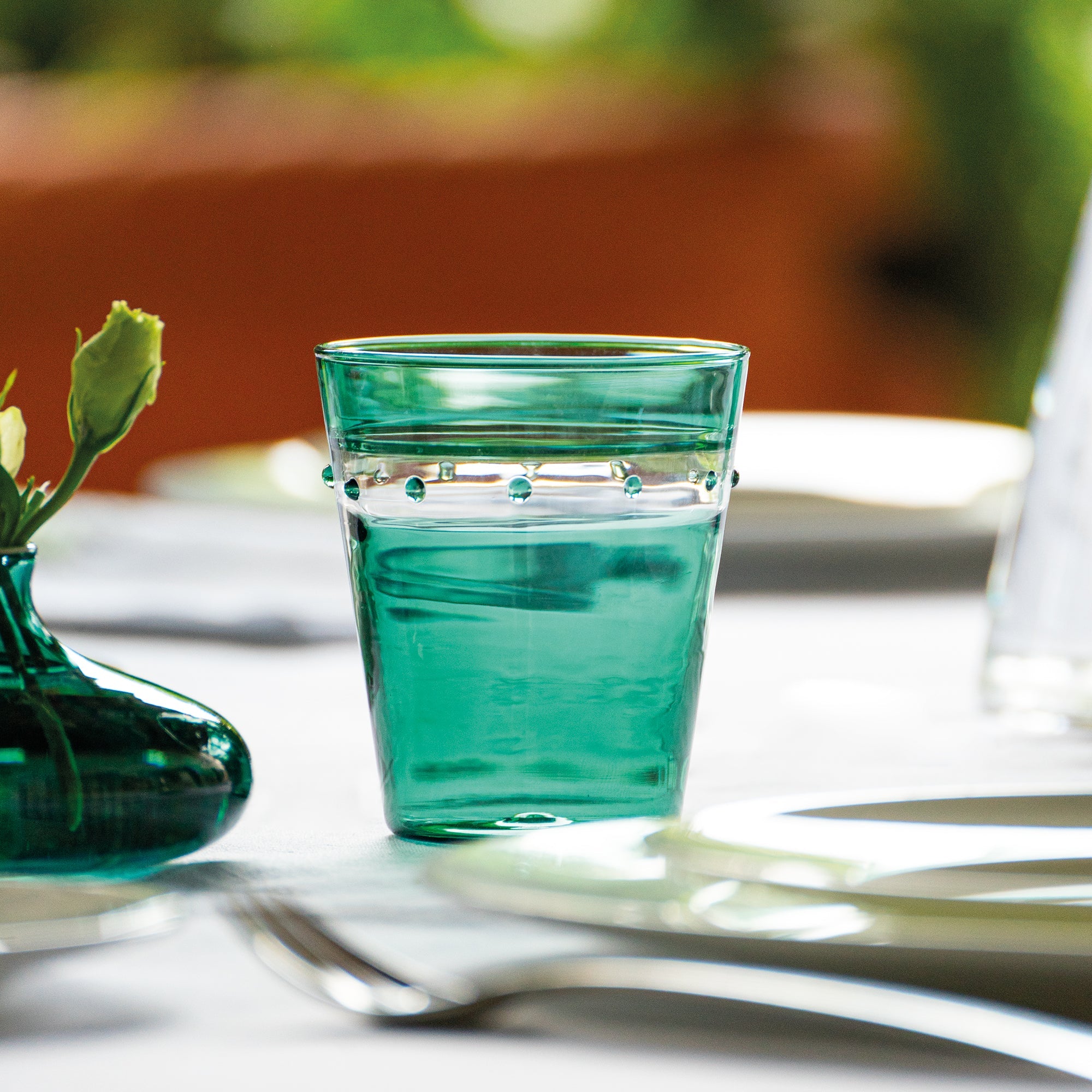 Green glass with water on a table with a blurred background