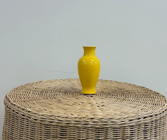 yellow vase on wicker table with white wall background