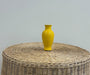 yellow vase on wicker table with white wall background