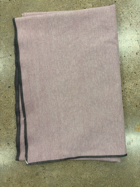 Folded blanket with black trim on a textured surface