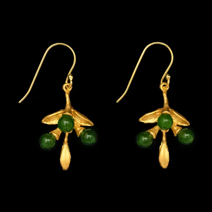 A pair of gold dangle earrings with green bead details, shown against a solid black background.