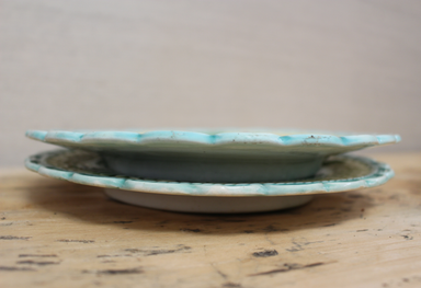 Two ceramic plates with a greenish-blue glaze on a wooden surface.