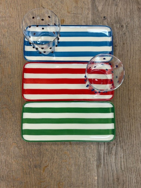 Set of three striped trays in blue, red, and green on a wooden surface.