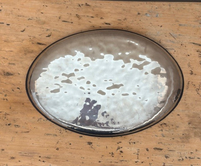 Round metal tray with a textured surface on a wooden table
