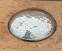 Round metal tray with a textured surface on a wooden table