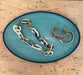 Chain and bracelets on a teal textured plate with a wooden background