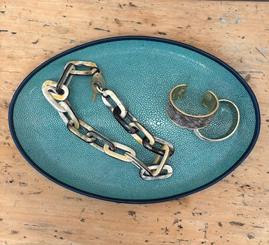 Chain and bracelets on a teal textured plate with a wooden background