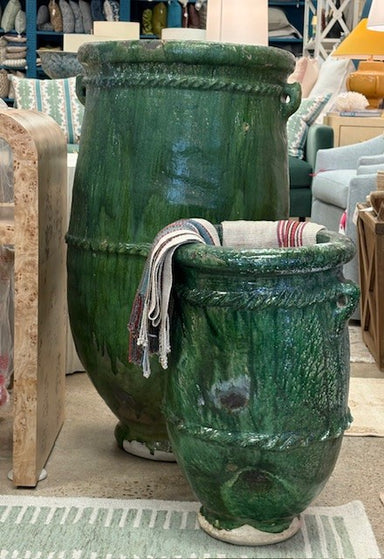 Two large green ceramic pots with a striped towel draped over them in an indoor setting.