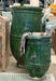 Two large green ceramic pots with a striped towel draped over them in an indoor setting.