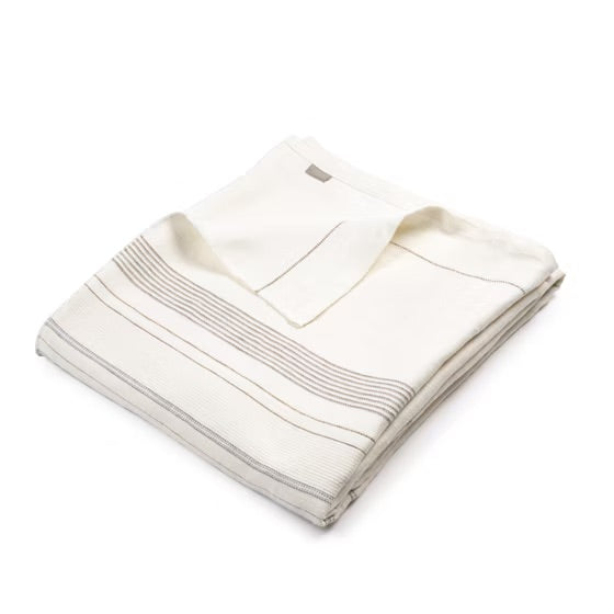 Folded beige coverlet with a brand logo on a white background