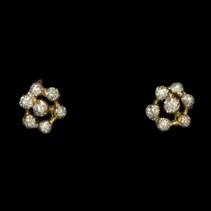 A pair of gold flower-shaped stud earrings set with small clear round gemstones, shown against a solid black background.