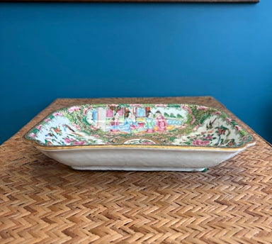 Decorative ceramic platter with a colorful design on a woven surface against a blue wall.