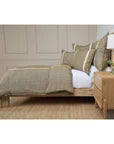 Bedroom with wooden bed frame, moss and flax bedding, and white pillows.