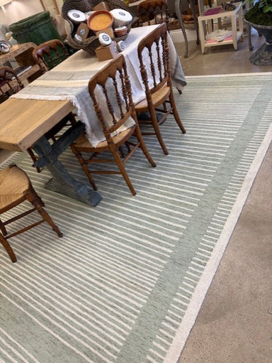 Striped rug on a floor with wooden furniture in the background