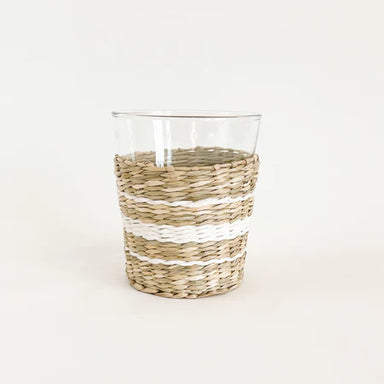 Clear glass with woven straw-like base on a white background