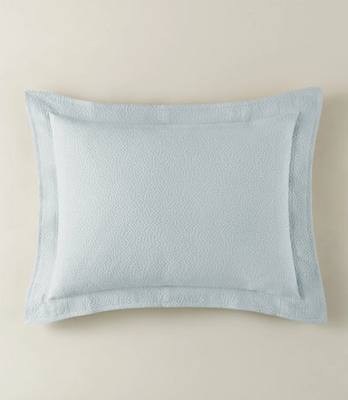 Light blue textured pillow on a beige background