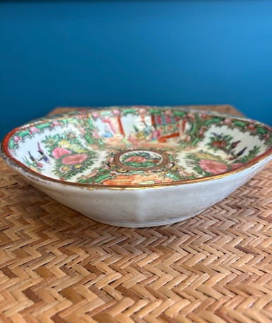 Decorative ceramic bowl with intricate patterns on a woven surface and blue background