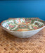Decorative ceramic bowl with intricate patterns on a woven surface and blue background