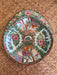 Decorative shrimp bowl with colorful floral and figurine design on a woven surface