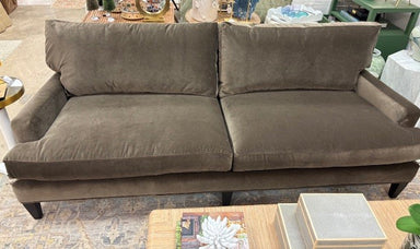 Brown sofa in a room with tables and decor items.